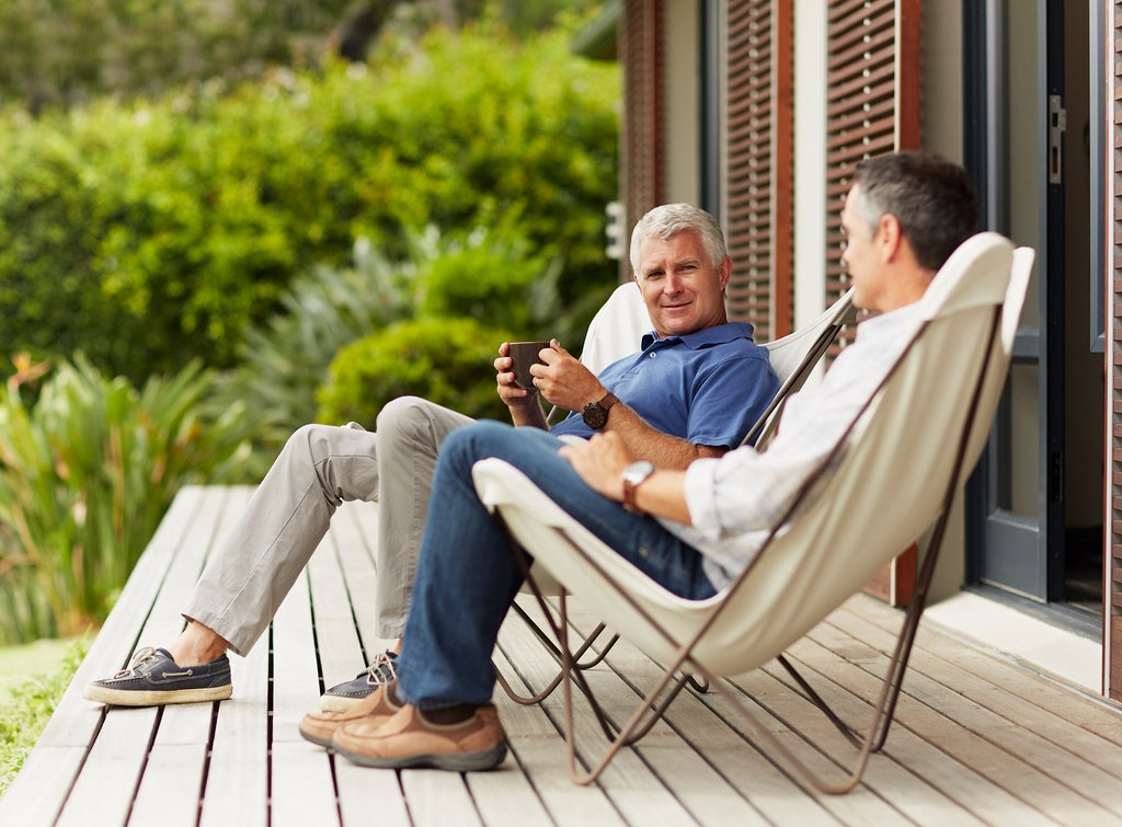 Genießen Sie Ihr Werk - mit uns ganz schnell. Zwei Männer mit Bechern in der Hand auf Holzterrasse